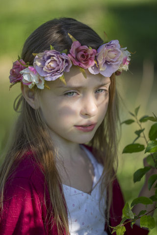 Portrait of daydreaming little girl wearing flowers stock photo