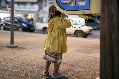 Back view of little girl using telephone booth stock photo