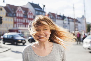 Porträt einer glücklichen Frau mit vom Wind zerzaustem Haar auf einer Stadtstraße - MASF05432