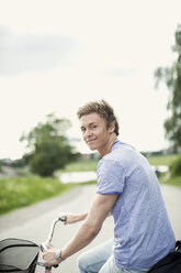 Porträt eines jungen Mannes auf dem Fahrrad auf dem Lande - MASF05436