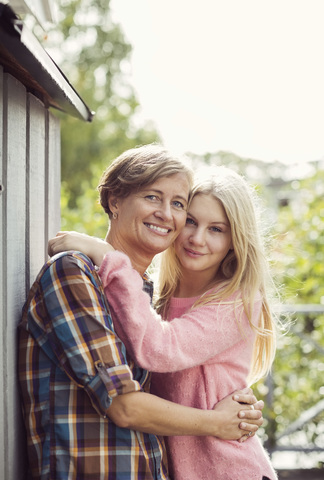 Porträt von Mutter und Tochter, die sich auf dem Hof umarmen, lizenzfreies Stockfoto