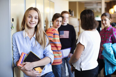 Porträt eines Schulmädchens, das in der Umkleidekabine steht, mit Freunden im Hintergrund - MASF05455