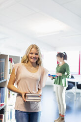 Portrait of smiling high school student holding books in library - MASF05462