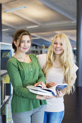 Porträt von Highschool-Freundinnen mit Büchern in der Bibliothek - MASF05464