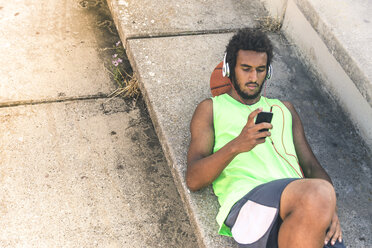 Basketball player listening music, smartphone and headphones - FMOF00334