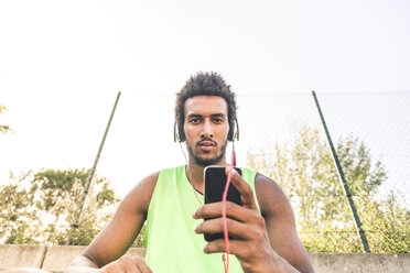 Basketball player listening music, smartphone and headphones - FMOF00336