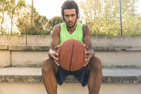 Young basketball player holding ball and listening music stock photo