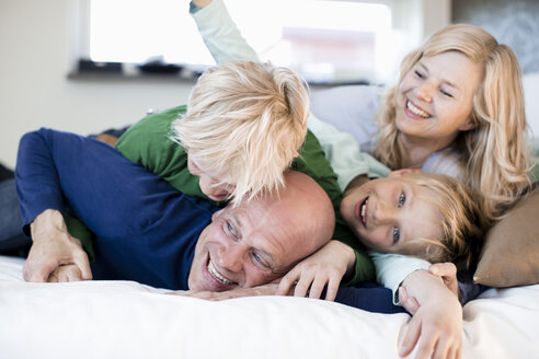 Porträt eines glücklichen Jungen mit Familie im Bett - MASF05478
