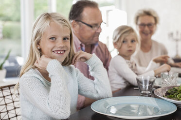 Porträt eines glücklichen Mädchens, das mit seiner Familie am Esstisch sitzt - MASF05501