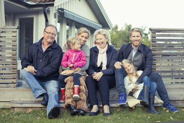 Porträt einer glücklichen Mehrgenerationen-Familie, die zusammen im Hof sitzt - MASF05502