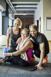 Portrait of happy instructors with senior woman at health club - MASF05511