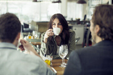 Reife Frau trinkt Kaffee, während sie einen Kollegen beim Mittagessen im Restaurant ansieht - MASF05542
