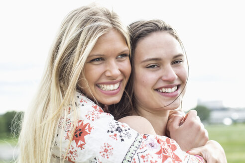 Glückliche junge Frau umarmt Freundin gegen klaren Himmel - MASF05592