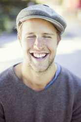 Happy man wearing flat cap outdoors - MASF05596