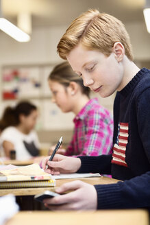 Gymnasiast benutzt Handy beim Lernen im Klassenzimmer - MASF05602