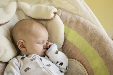 High angle view of baby boy sucking thumb while sleeping in bassinet - CAVF43014