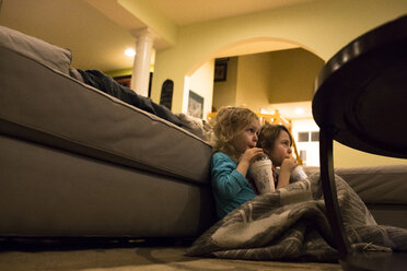Siblings looking away while enjoying drinks by sofa at home - CAVF43029
