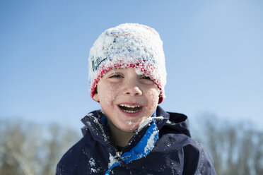 Porträt eines glücklichen, mit Schnee bedeckten Jungen vor einem klaren blauen Himmel - CAVF43039