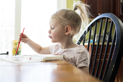 Mädchen malt am Tisch zu Hause, lizenzfreies Stockfoto