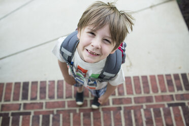 High angle portrait of boy with backpack standing on steps - CAVF43052