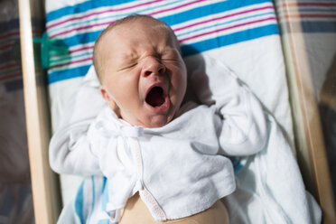 Close-up of baby boy yawning while sleeping in crib at hospital - CAVF43067