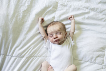 High angle view of baby boy stretching on bed at home - CAVF43075