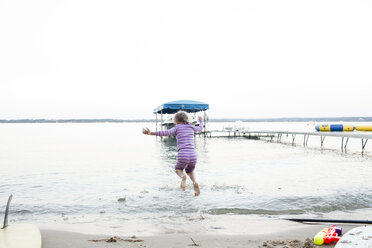 Rear view of girl jumping at beach against clear sky - CAVF43081