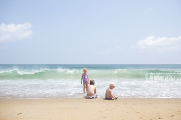 Geschwister spielen am Strand gegen den Himmel an einem sonnigen Tag - CAVF43086