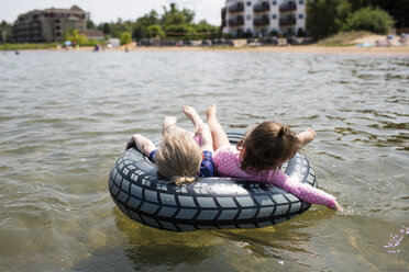 Sisters relaxing on inflatable ring in sea - CAVF43125