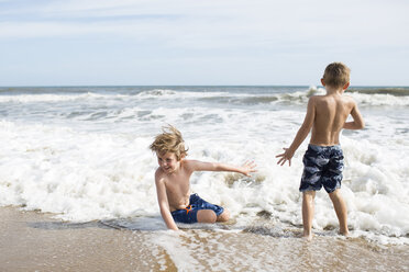 Brothers enjoying at beach against sky during sunny day - CAVF43134