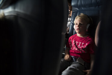 Junge schaut weg, während er im Flugzeug Musik hört - CAVF43162