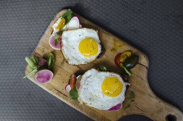 High angle view of fried eggs with bread and vegetables on serving board - CAVF43167