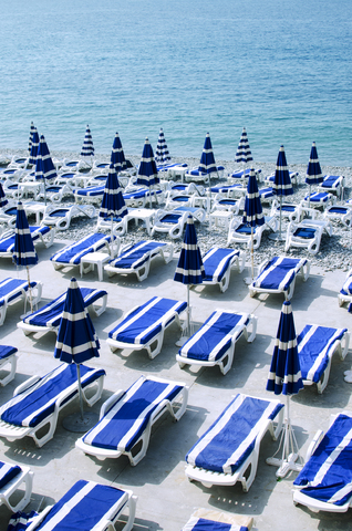 High angle view of deck chairs with parasols arranged at beach during sunny day stock photo