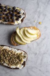 High angle view of toasted breads with pumpkin seeds and fruits on table - CAVF43178