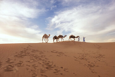 Menschen zu Fuß mit Kamelen auf Sand in der Wüste gegen den Himmel - CAVF43180