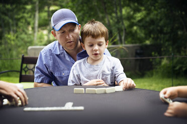 Vater und Sohn spielen Domino am Tisch im Hinterhof - CAVF43184