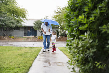 Großvater und Enkelin gehen unter einem Regenschirm auf einem Fußweg im Park spazieren - CAVF43217