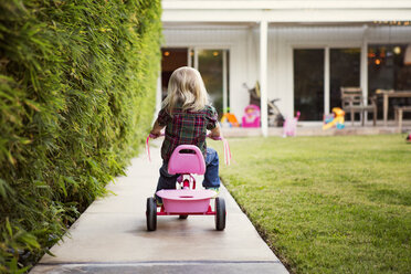 Rückansicht eines Mädchens auf einem Dreirad im Hof - CAVF43229