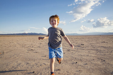 Portrait of happy boy running on arid landscape - CAVF43233