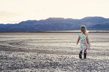 Rückansicht eines Mädchens, das durch eine trockene Landschaft läuft - CAVF43236