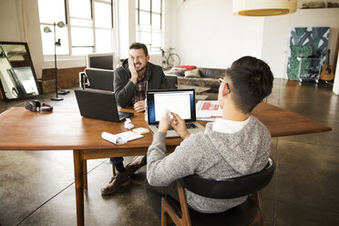 Geschäftspartner unterhalten sich mit Laptops am Tisch im Büro - CAVF43281