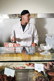 Metzger schneidet frisches Fleisch für den Verkauf im Geschäft - CAVF43391