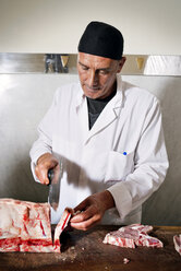 Butcher chopping fresh meat for sale at counter in shop - CAVF43392
