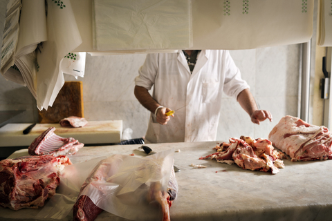 Midsection of butcher chopping meat at counter in shop stock photo