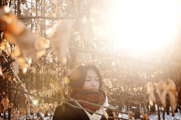 Nachdenkliche Frau inmitten von Bäumen an einem sonnigen Tag im Winter - CAVF43406