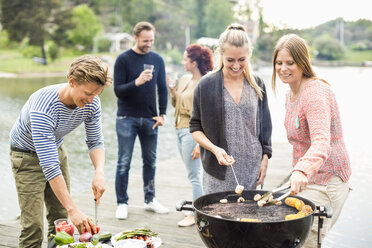 Group of friends enjoying barbecue party on pier - MASF05614