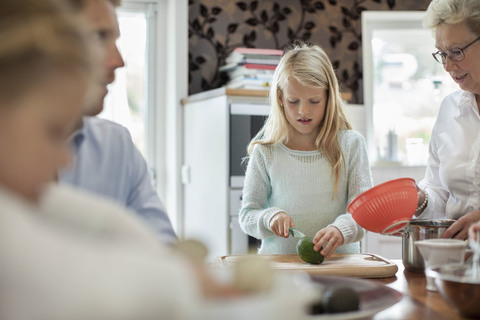 Mädchen schneidet Gemüse beim Kochen mit der Familie in der Küche, lizenzfreies Stockfoto