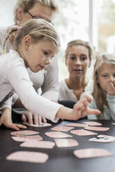 Mädchen spielt Kartenpuzzle mit Familie zu Hause - MASF05641