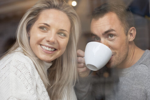 Glückliches Paar schaut aus dem Fenster eines Cafés - MASF05644