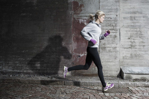 Frau in voller Länge beim Joggen auf der Straße, lizenzfreies Stockfoto